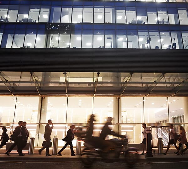 Busy street outside lighted office building at night