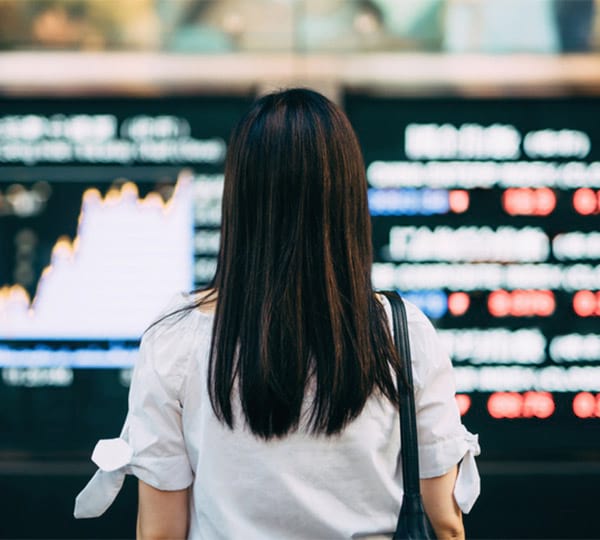 Back of a woman looking at a monitor with chart and numbers